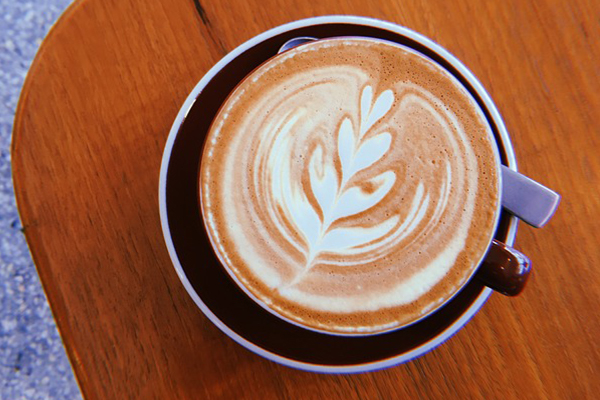 latte art in mug on wooden board